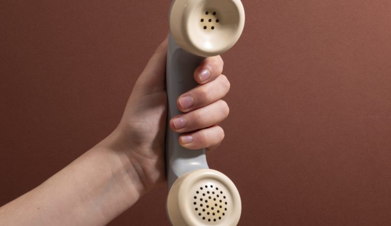 hand-holding-phone-with-brown-background